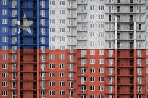 Chile flag depicted in paint colors on multi-storey residental building under construction. Textured banner on brick wall background photo