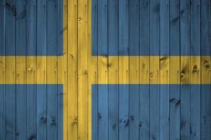 Sweden flag depicted in bright paint colors on old wooden wall. Textured banner on rough background photo