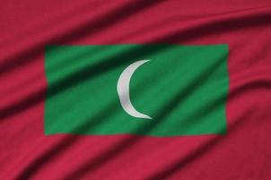 Maldives flag  is depicted on a sports cloth fabric with many folds. Sport team banner photo