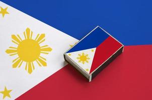 Philippines flag  is pictured on a matchbox that lies on a large flag photo