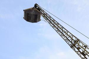 Old yellow mechanical clamshell grab on blue sky background photo