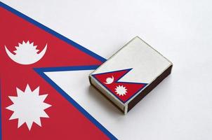 Nepal flag  is pictured on a matchbox that lies on a large flag photo