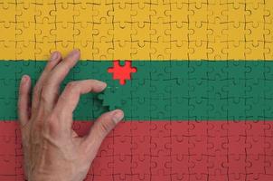 Lithuania flag  is depicted on a puzzle, which the man's hand completes to fold photo