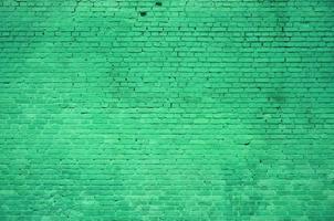 The texture of the brick wall of many rows of bricks painted in green color photo