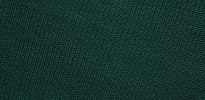 Texture of smooth knitted dark green sweater with pattern. Top view, close-up. Handmade knitting wool or cotton fabric texture. Background of Large Ribs knit pattern with knitting needles or crochet. photo