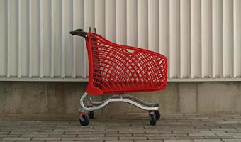 Empty red shopping on industrial wall background. Shop trolley at supermarket. Sale, discount, shopaholism, black friday, economy concept. Consumer society trend. Online Shopping Concept. photo