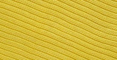 Texture of smooth knitted yellow sweater with pattern. Top view, close-up. Handmade knitting wool or cotton fabric texture. Background of knitting patterns. photo