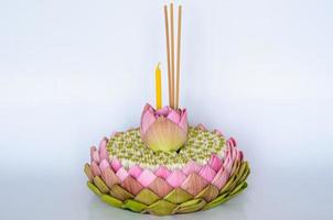 krathong de pétalos de loto rosa que tiene 3 varitas de incienso y velas decoradas con loto y flor de corona para la luna llena de tailandia o el festival loy krathong sobre fondo blanco. foto