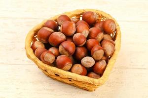 Hazelnut heap in a basket on wooden background photo