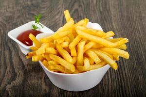 French fries in a bowl on wooden background photo