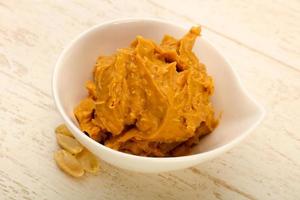 Peanut butter in a bowl on wooden background photo