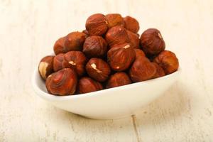 Hazelnut heap in a bowl on wooden background photo