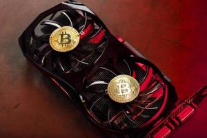 On the fans of a powerful video card, the coins of the Bitcoin cryptocurrency with a red backlight are displayed. photo