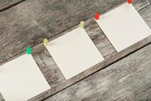 Square stickers pinned in a row on a wooden table. photo