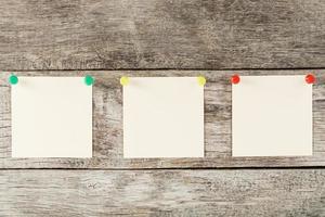 Sticky notes with pins in a row on a wooden background. photo