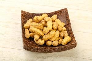 Unpeeled peanuts in a bowl on wooden background photo