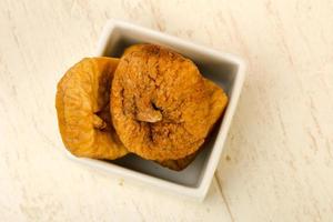 Dry figs in a bowl on wooden background photo