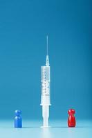 Vaccinate or refuse a syringe with a vaccine with two groups of people a red and a blue human model. photo