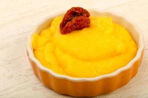 Polenta in a bowl on wooden background photo