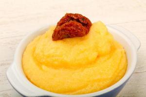 Polenta in a bowl on wooden background photo