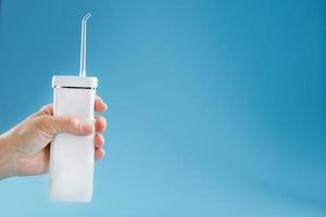 Irrigator in hand for cleaning the mouth on a blue background. photo