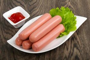Sausages on the plate and wooden background photo