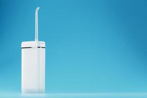 Mobile irrigator for cleaning the oral cavity on a blue background. photo