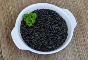 Black caviar in a bowl on wooden background photo