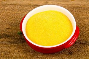 Raw polenta in a bowl on wooden background photo