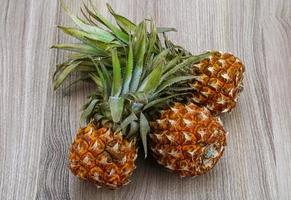 Small pineapple on wooden background photo