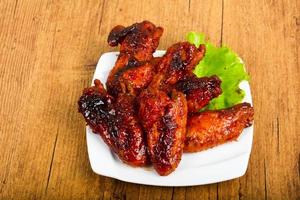 Chicken wings on the plate and wooden background photo