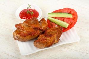 Pork BBQ on the plate and wooden background photo