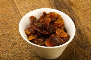 Dry Raisin in a bowl on wooden background photo