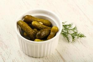 Picled cucumbers in a bowl on wooden background photo
