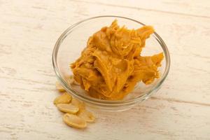 Peanut butter in a bowl on wooden background photo