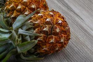 Small pineapple on wooden background photo