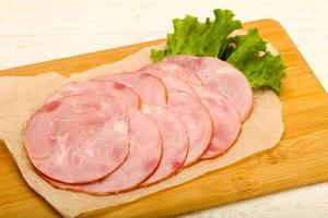 Sliced sausage on wooden board and wooden background photo