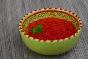 Red caviar in a bowl on wooden background photo