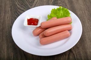 Sausages on the plate and wooden background photo