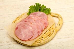 Sliced sausage on wooden board and wooden background photo
