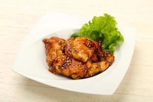 Teriyaki thighs on the plate and wooden background photo