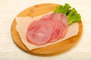 Sliced sausage on wooden board and wooden background photo