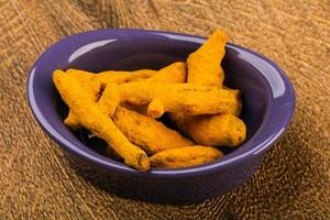 Tumeric roots in a bowl on wooden background photo