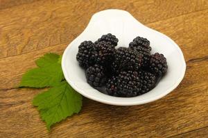 moras en un recipiente sobre fondo de madera foto