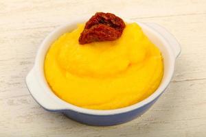 Polenta in a bowl on wooden background photo