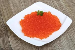 Red caviar on the plate and wooden background photo