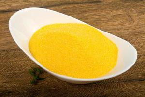 Raw polenta in a bowl on wooden background photo