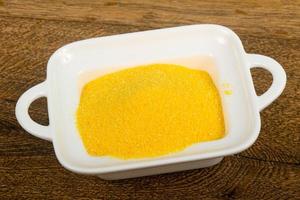 Raw polenta in a bowl on wooden background photo