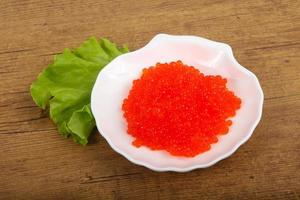 Red caviar on the plate and wooden background photo