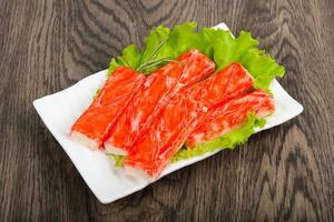 Crab sticks on the plate and wooden background photo